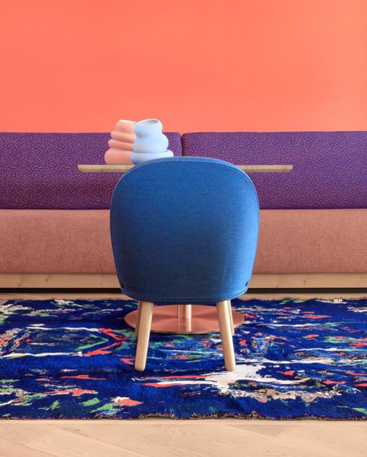 Tisch mit blauem Stuhl und buntem Teppich